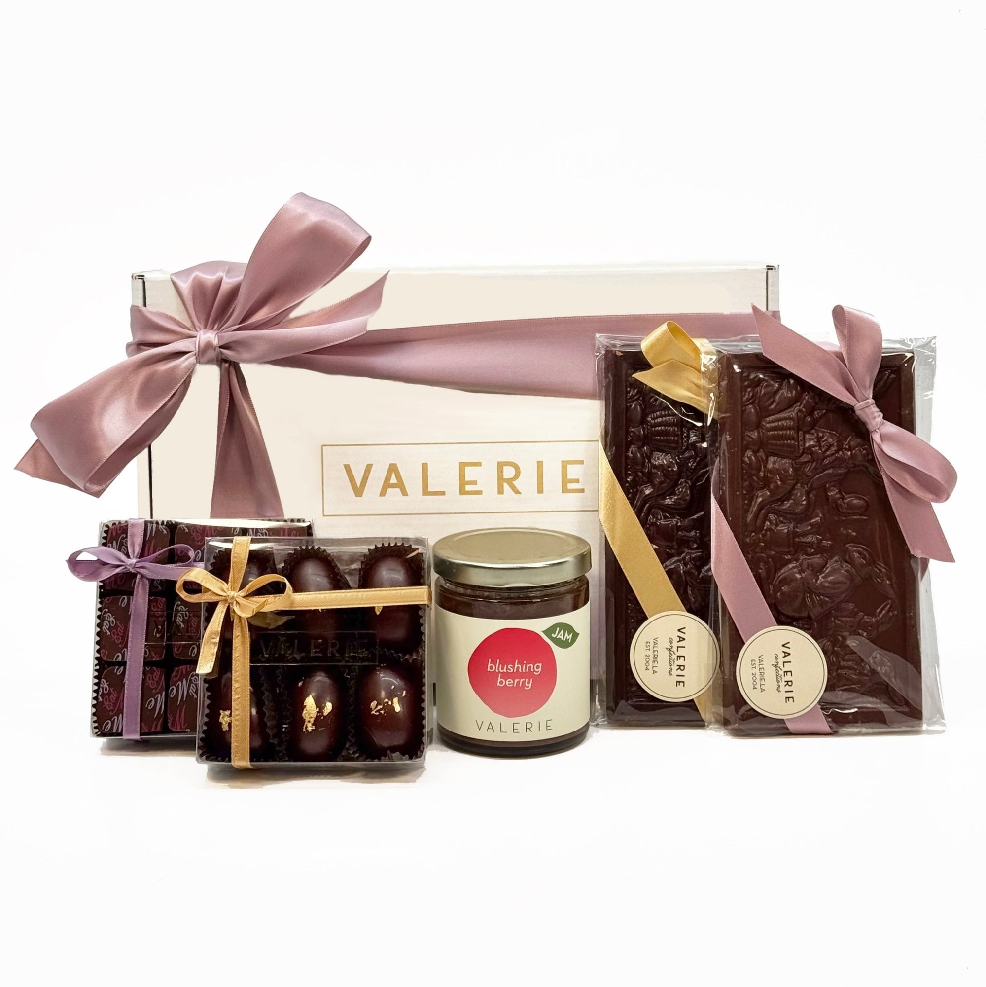 A beautifully arranged Easter Gift Set from Valerie Confections, featuring Golden Eggs, Eat Me Truffle Box, Blushing Berry Jam, and two tableau chocolate bars, all elegantly packaged with satin ribbons.