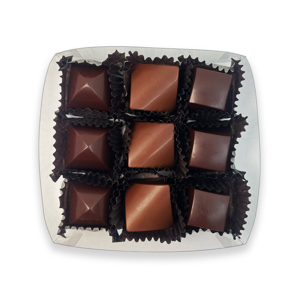 A box of nine handcrafted truffles from the Happy Hour Truffle Box by Valerie Confections, featuring scotch, champagne, and mezcal caramel ganache chocolates in elegant geometric shapes.