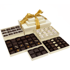 The Isabelle Gift Tower unwrapped, revealing an elegant assortment of chocolates, petits fours, and toffee in ivory boxes with a golden ribbon.