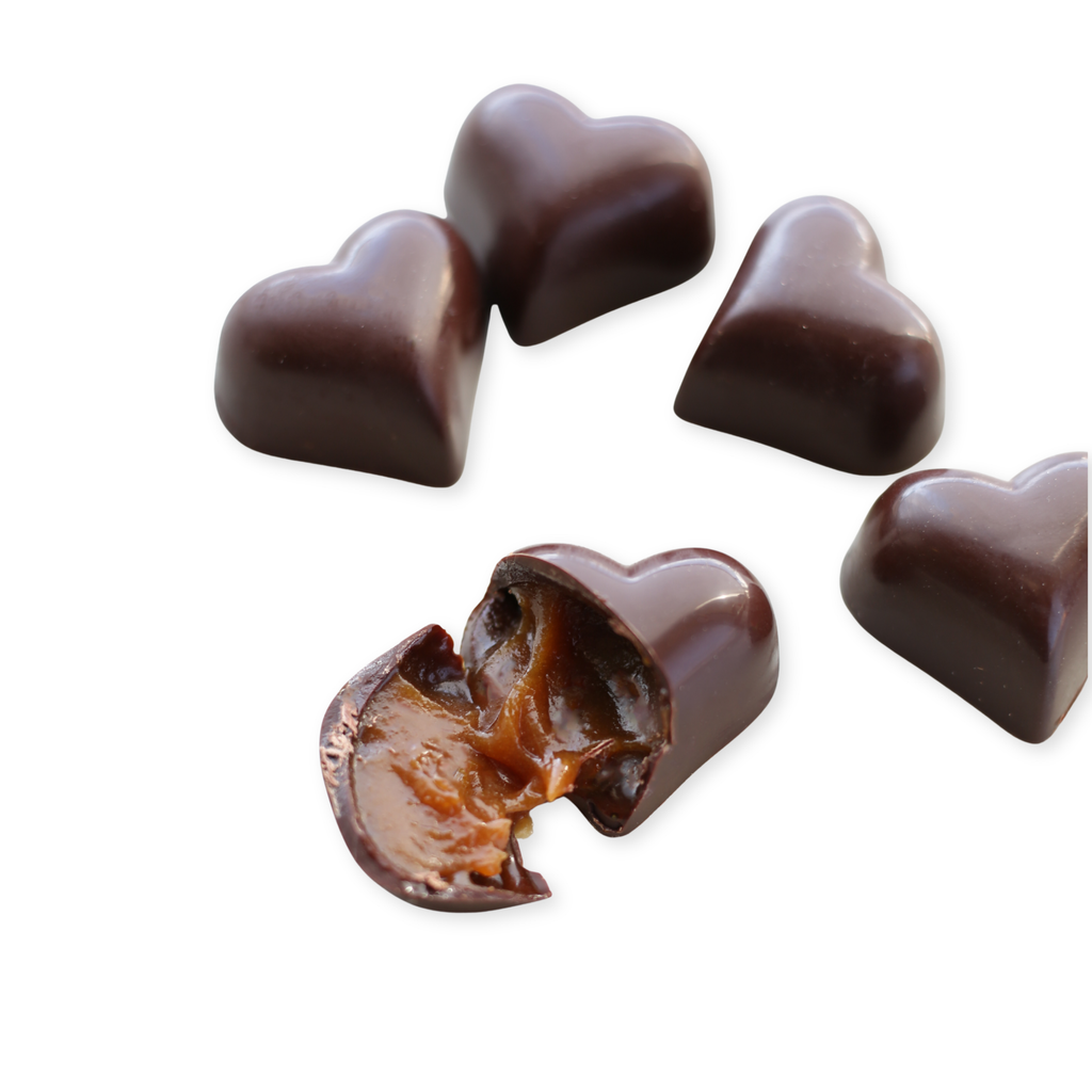 Heart-shaped chocolates with one broken open on a white background
