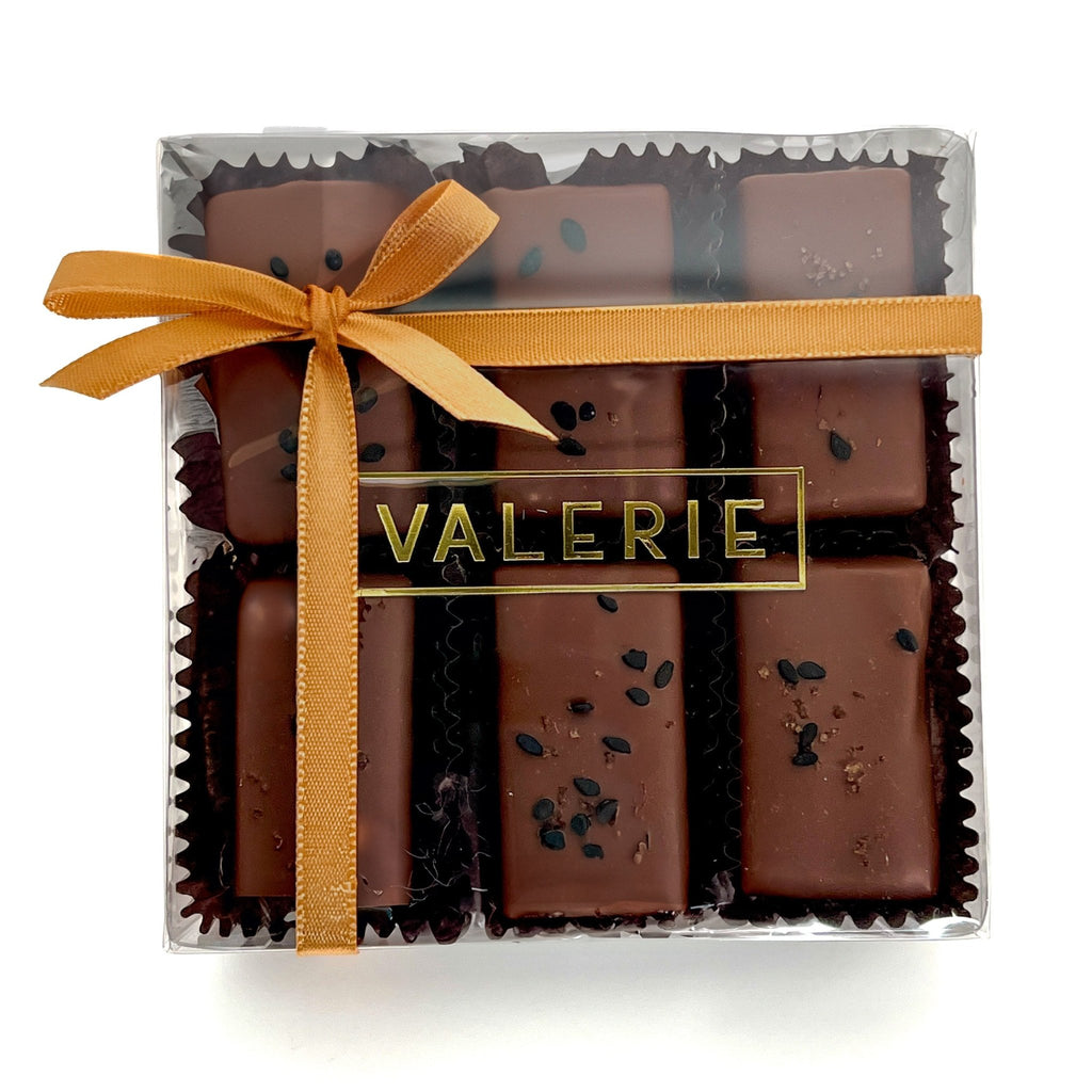  box of Rice & Sesame Caramels from Valerie Confections, featuring chocolate-covered caramels topped with black sesame seeds and soy salt, wrapped in an elegant golden ribbon.