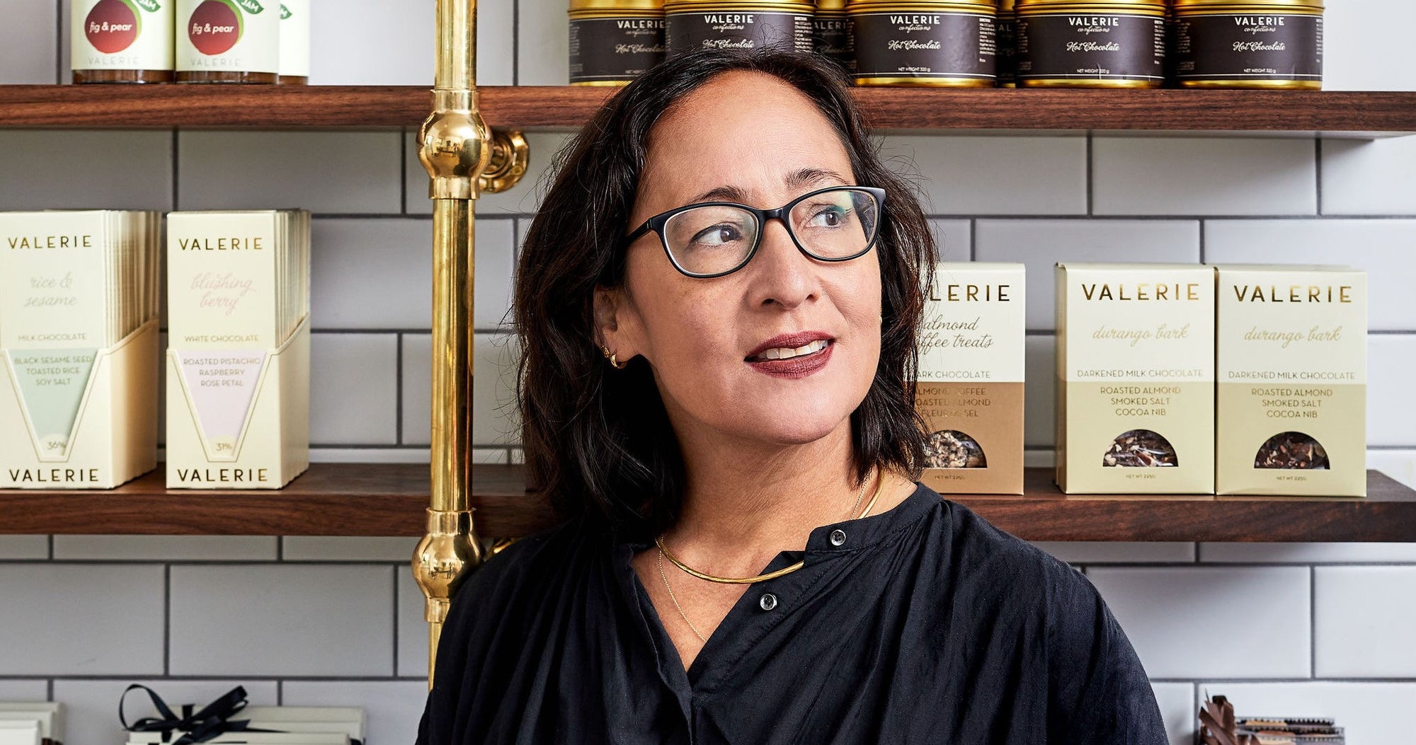 Valerie Gordon standing in front of a shelf with "VALERIE" branded chocolate products.