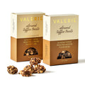Two boxes of Almond Toffee Treats with pieces of bite-sized chocolate-covered toffee, rolled in roasted almonds and Fleur de Sel, displayed in front.