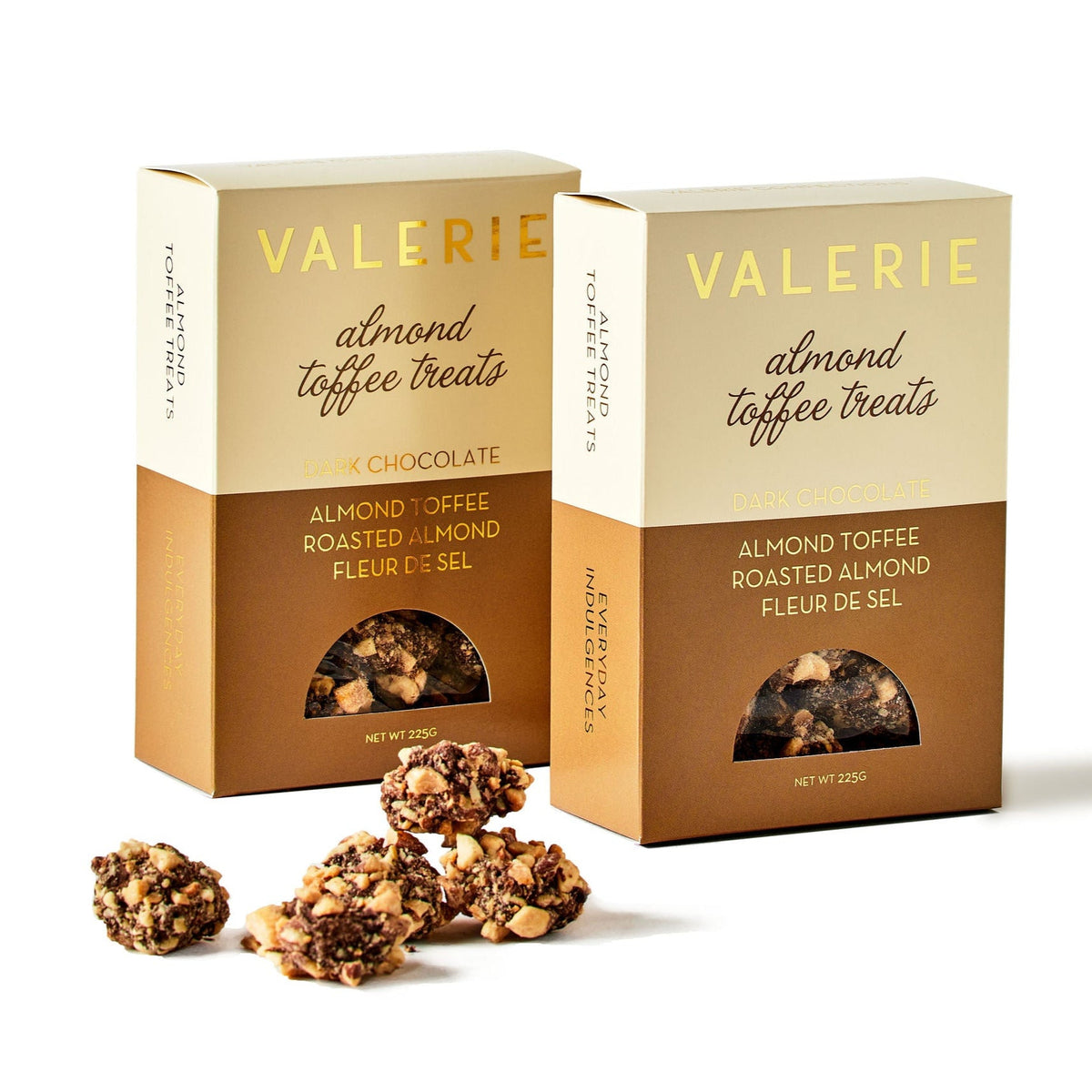Two boxes of Almond Toffee Treats with pieces of bite-sized chocolate-covered toffee, rolled in roasted almonds and Fleur de Sel, displayed in front.