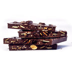 Stacked pieces of GOOD MIX BAR, showing almonds, sesame seeds, raisins, and spices embedded in dark chocolate.