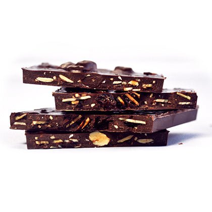 Stacked pieces of GOOD MIX BAR, showing almonds, sesame seeds, raisins, and spices embedded in dark chocolate.