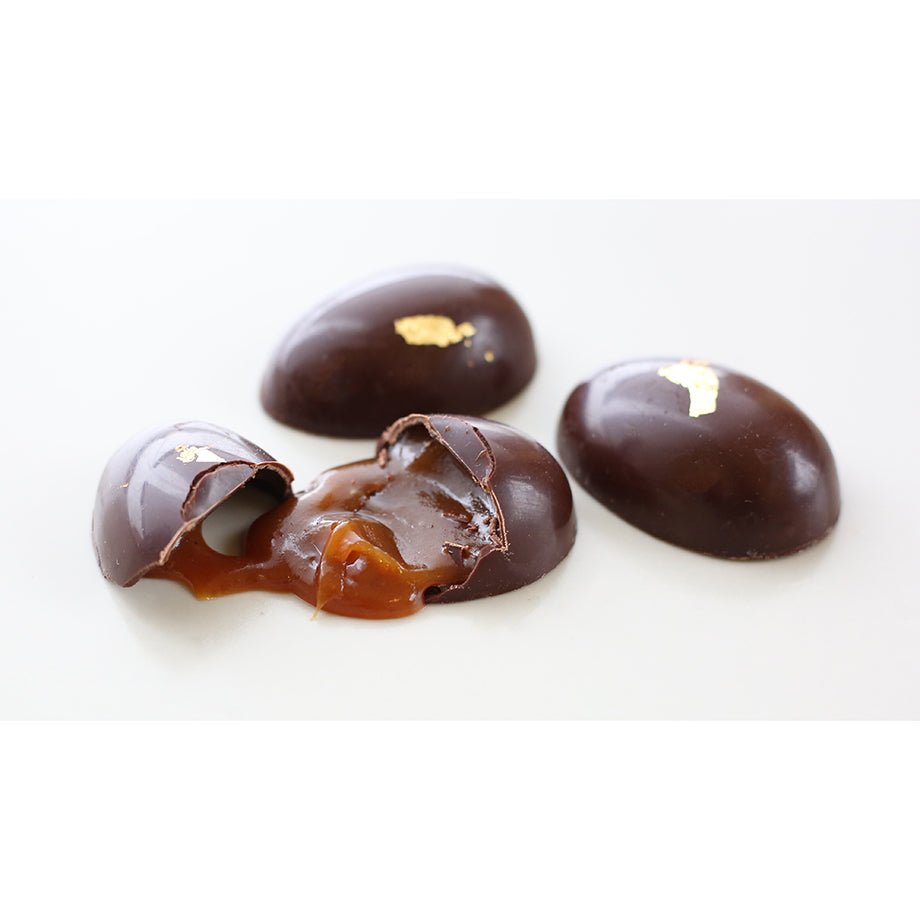 Close-up of Golden Eggs - Bittersweet chocolate eggs filled with liquid caramel, adorned with edible gold leaf.