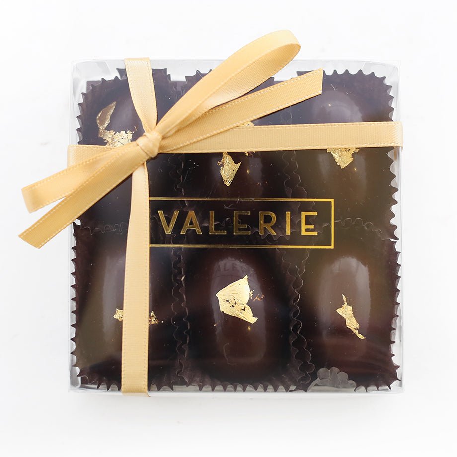 Golden Eggs in a clear gift box tied with a golden ribbon, featuring 6 decadent chocolate eggs.