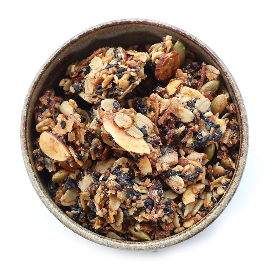 A bowl of Valerie Confections House Granola, featuring a mix of oats, almonds, sunflower seeds, pepitas, and black sesame seeds.