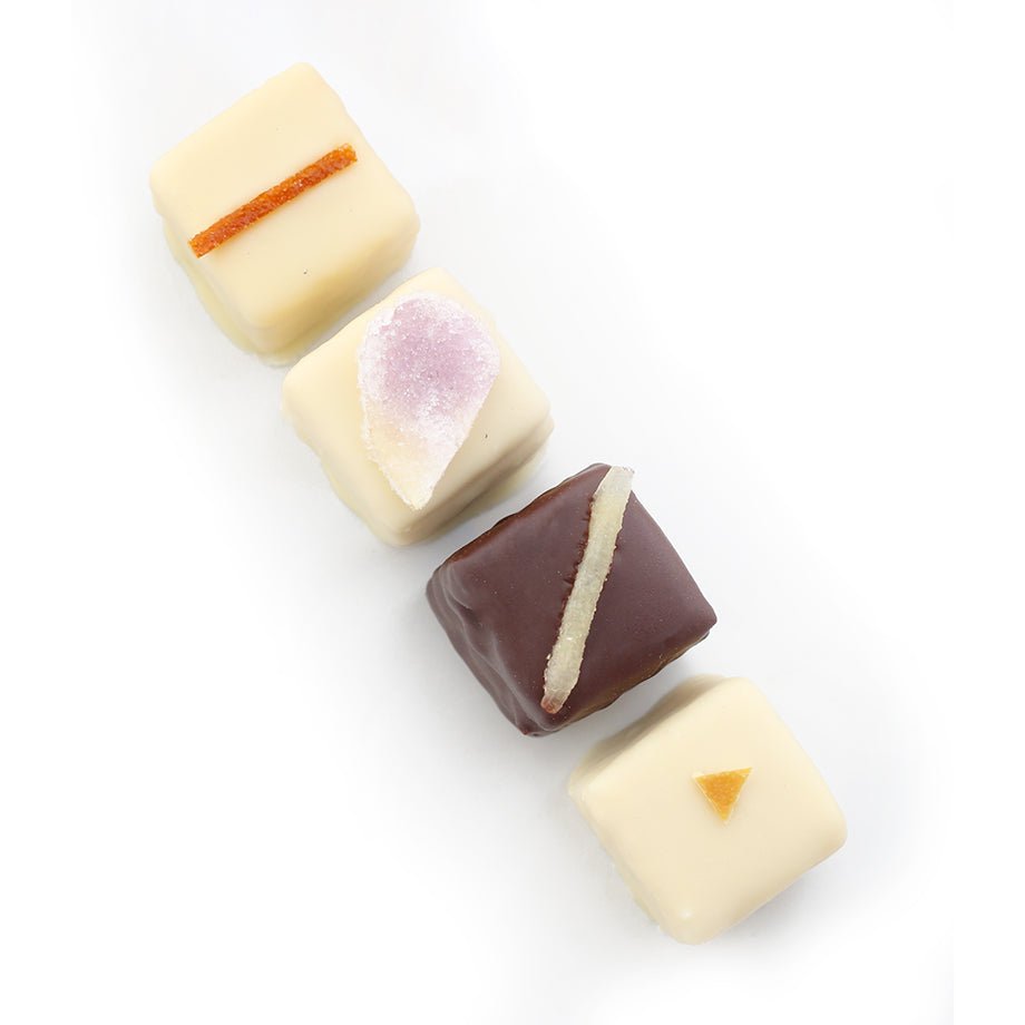 A close-up of an assortment of gourmet petits fours, featuring layers of cake and delicate chocolate coatings, elegantly decorated.