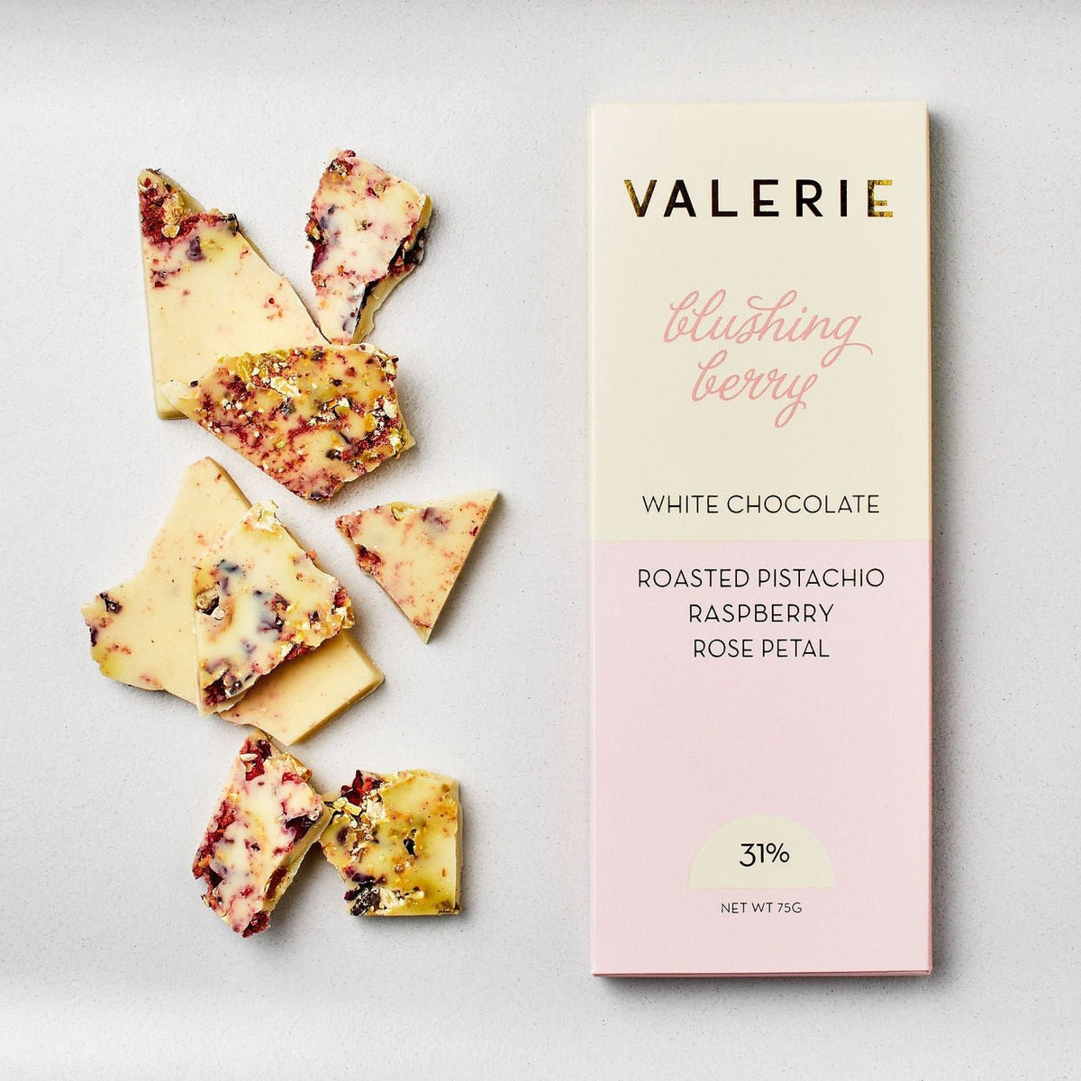 White chocolate with raspberry, pistachio, and rose petals beside product packaging labeled Valerie Blushing Berry Bar