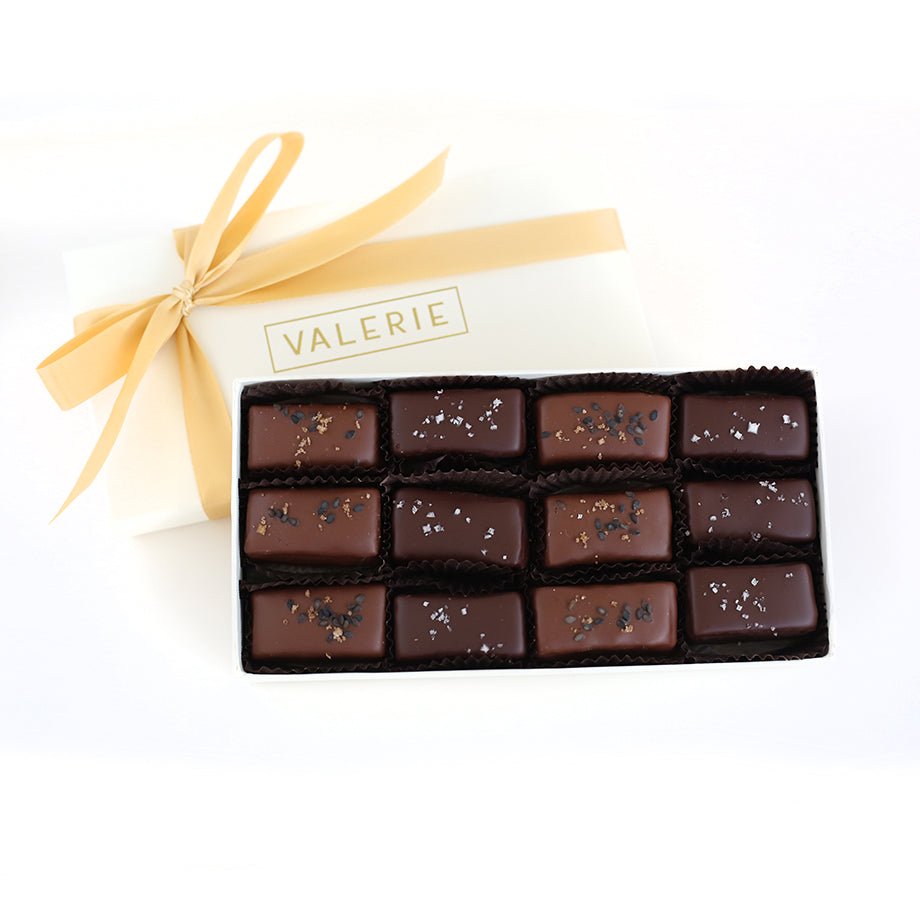 Box of alternating caramels, milk chocolate rice &amp; sesame and bittersweet fleur de sel, with a gold ribbon and the name &quot;Valerie&quot; on the cover.