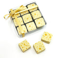 Box of twelve square eggnog truffles decorated with golden snowflakes, tied with a golden ribbon.