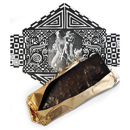 A chocolate bar partially wrapped in gold foil lying on top of black and white geometric packaging featuring classical nude figures.