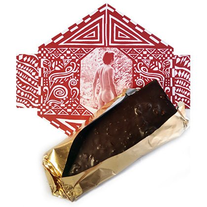 A chocolate bar partially wrapped in gold foil lying on top of red and white geometric packaging featuring classical nude figures.