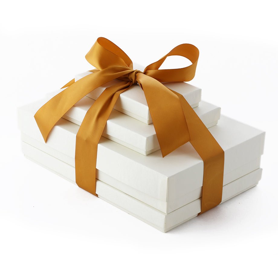 Stack of five ivory gift boxes with a golden ribbon bow.