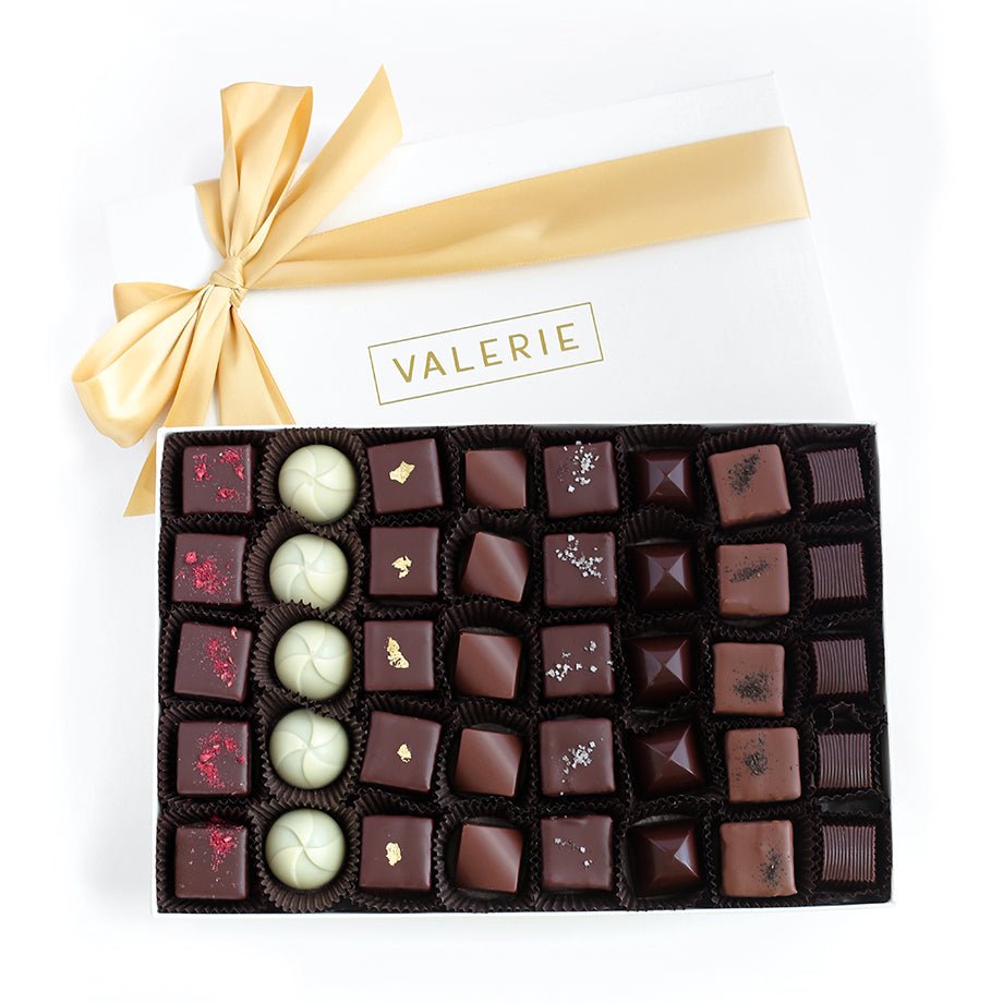 Open box of assorted luxury chocolates with a gold ribbon and the brand name “VALERIE” on the lid.