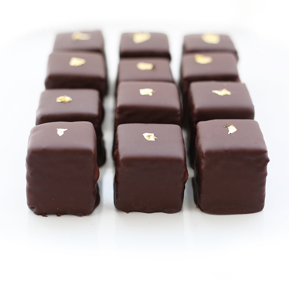 Close-up of luxury Champagne Petits Fours, highlighting the dark chocolate coating and gold leaf decoration.