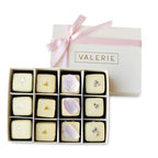 A luxury 12-piece Petit Four Bouquet gift box from Valerie Confections, wrapped in a soft pink ribbon, featuring handcrafted petits fours enrobed in white chocolate.