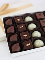 A close-up of a luxurious chocolate truffle assortment, highlighting gold leaf-adorned truffles, Matcha, Earl Grey, and Liquid Caramel chocolates.