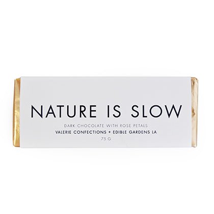 Nature Is Slow chocolate bar with white packaging and black text, featuring dark chocolate with rose petals.