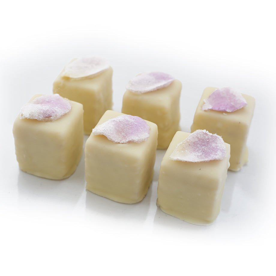  Six white chocolate petits fours topped with pink candied rose petals.