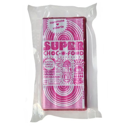 A close-up of the SUPER CHOC-O-FOOD bar in its Pink packaging, featuring intricate typography and bold design elements.