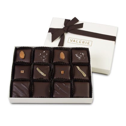 A white box of chocolates with a dark brown ribbon and twelve assorted toffee pieces inside.