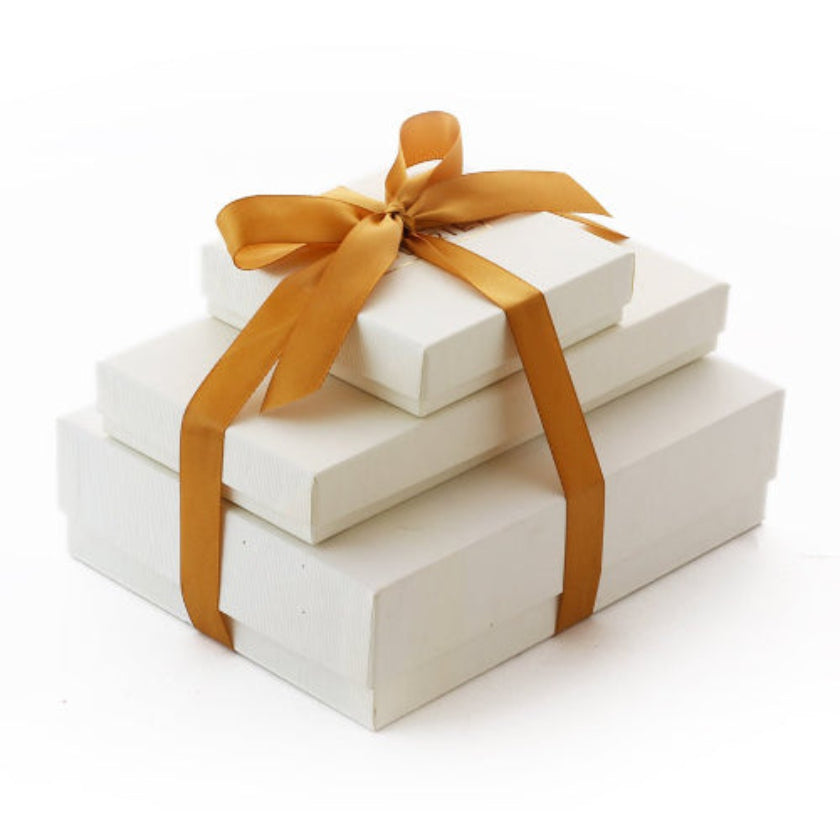 A beautifully stacked gift tower with gold ribbon, featuring artisanal chocolates and confections.