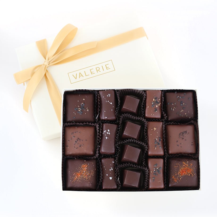 A box labeled &quot;VALERIE&quot; with a golden ribbon, partially opened to reveal an assortment of 16 toffees and caramels.